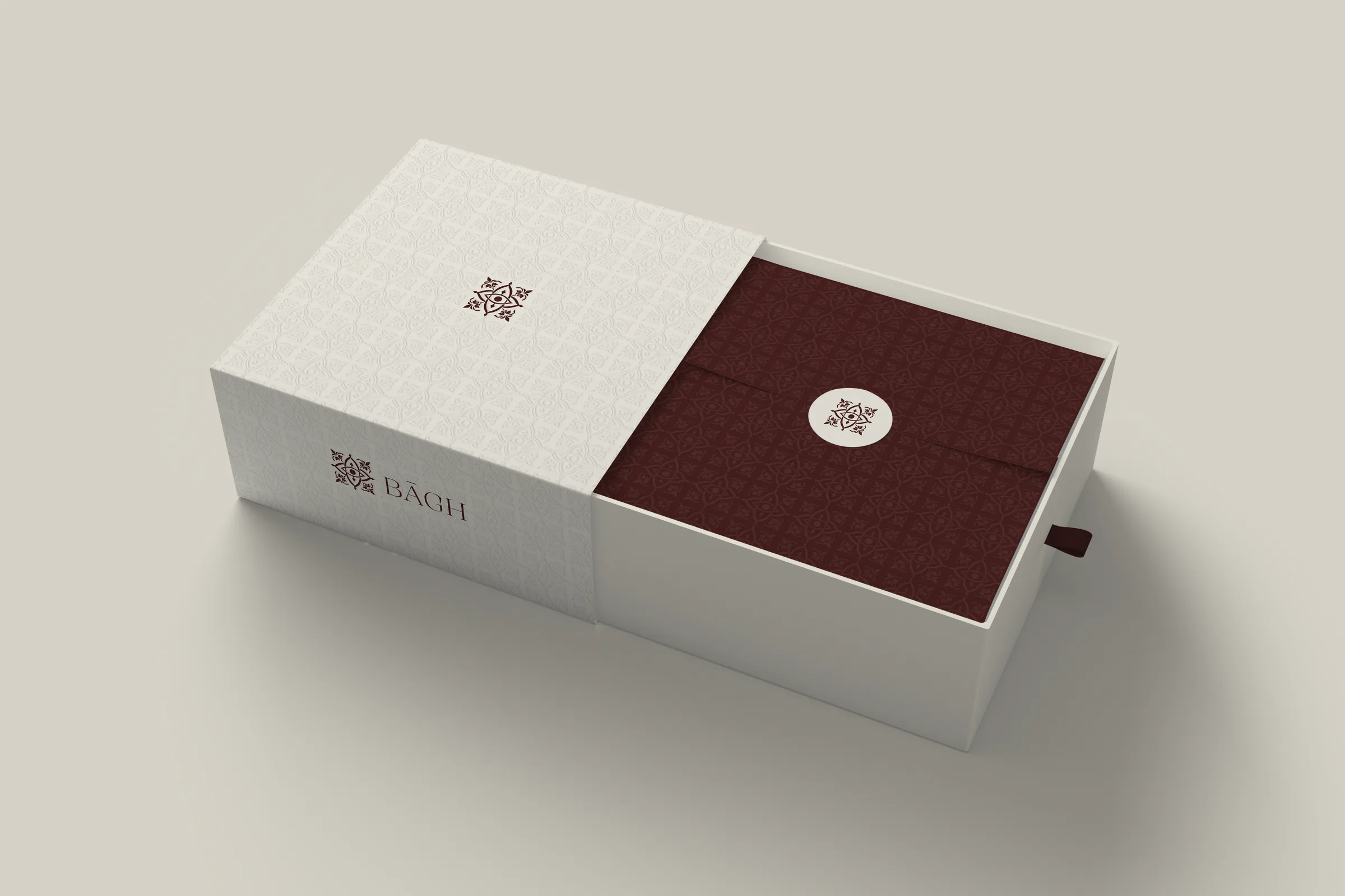 BĀGH rigid box with embossed cream sleeve and burgundy pattern tissue sealed with an emblem sticker