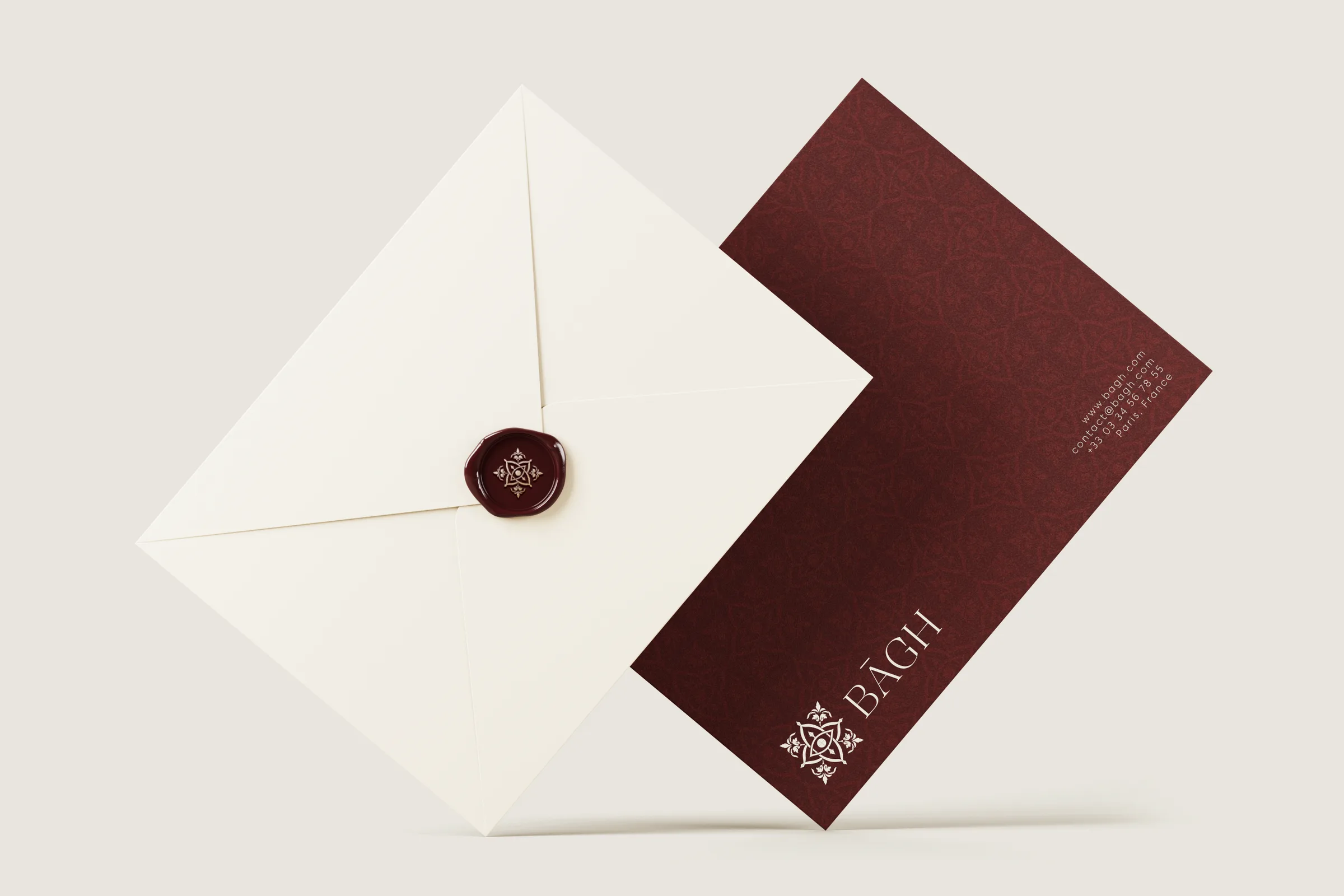 Cream envelope with burgundy wax seal beside a burgundy card
